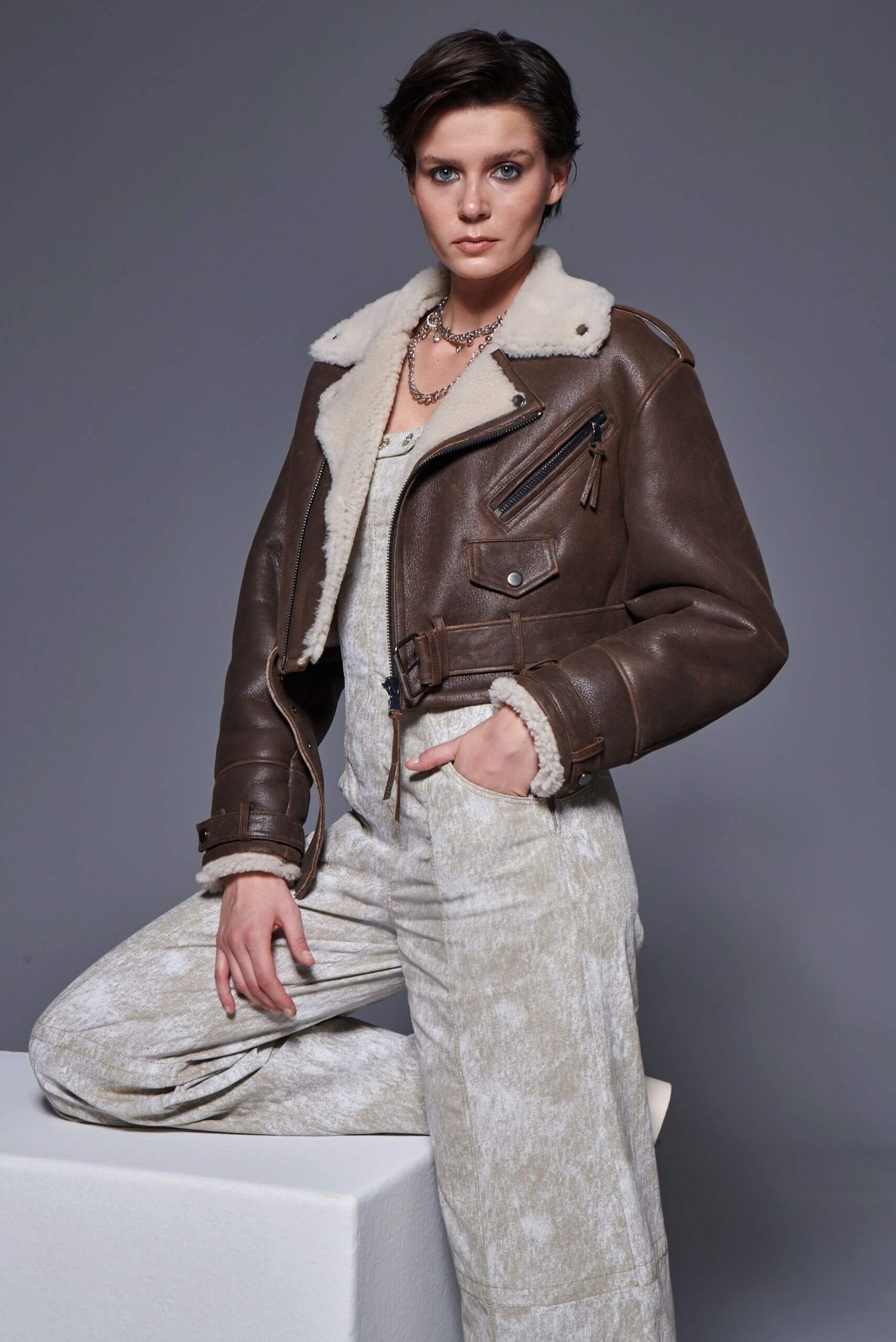 Woman wearing a brown shearling leather jacket, classic and cozy fashion style